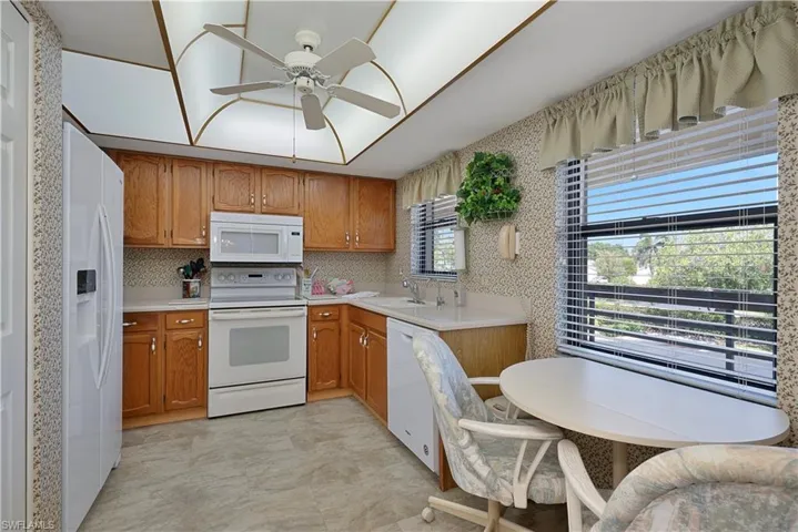 Kitchen with white appliances, light countertops and a ceiling fan
