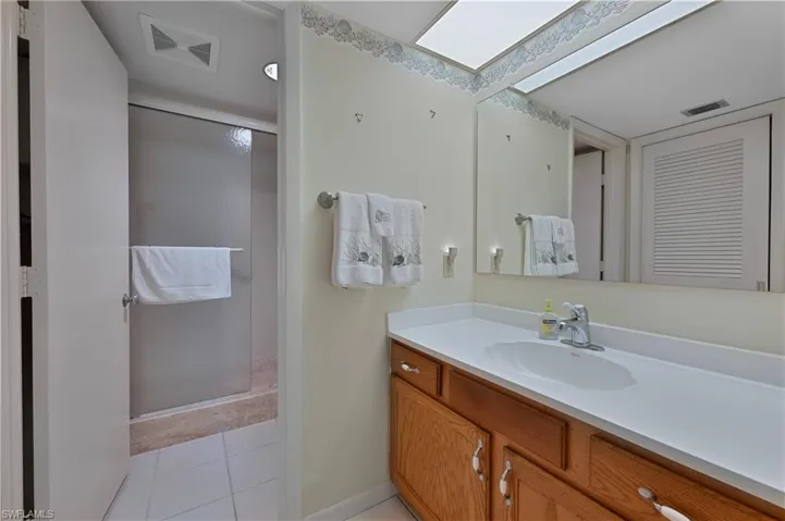Full bathroom with vanity, light tile floors, and a shower stall