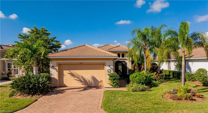 Front of home with lush landscaping, two car garage and screened in front porch