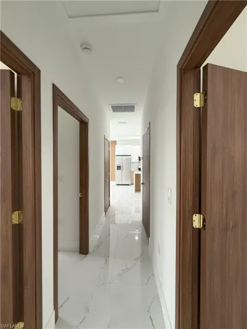 Hallway featuring light marble finish flooring and recessed lighting