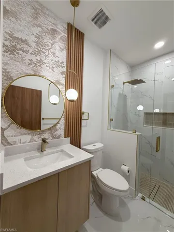Bathroom featuring vanity and a marble finish shower