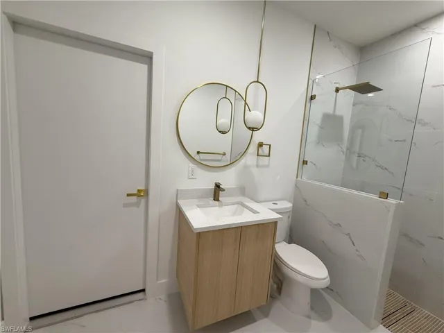 Bathroom featuring a marble finish shower and vanity