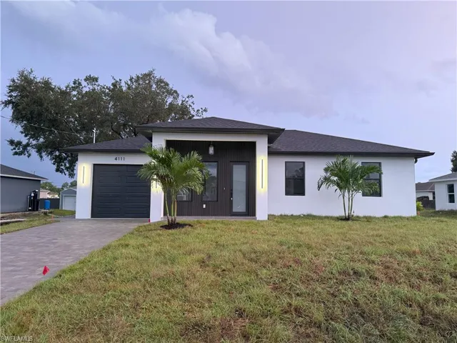 View of front of home with an attached garage, a front lawn, decorative driveway, and stucco siding