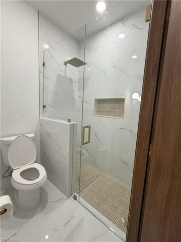Full bath featuring a marble finish shower and marble finish flooring