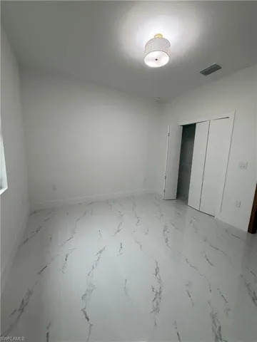Unfurnished bedroom featuring a closet and light marble finish floors