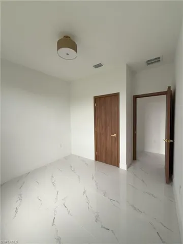Unfurnished bedroom with light marble finish flooring and baseboards