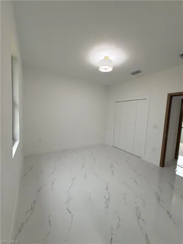 Unfurnished bedroom with a closet and marble finish flooring