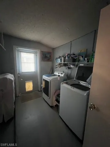 Laundry room featuring separate washer and dryer, lofted ceiling, a textured ceiling, and finished concrete flooring