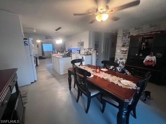 Dining area with concrete floors, ceiling fan, and a textured ceiling