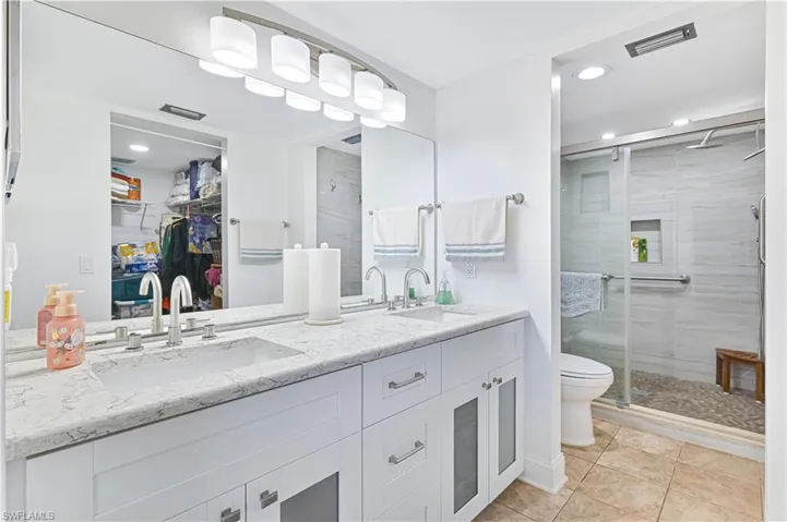 Bathroom featuring a spacious closet, double vanity, a shower stall, recessed lighting, and light tile patterned flooring