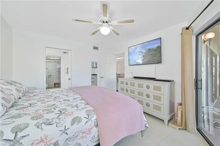Bedroom with ceiling fan, tile patterned flooring, and ensuite bath