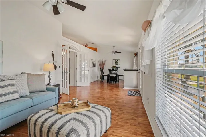 Living area featuring a ceiling fan, lofted ceiling, wood finished floors, and french doors