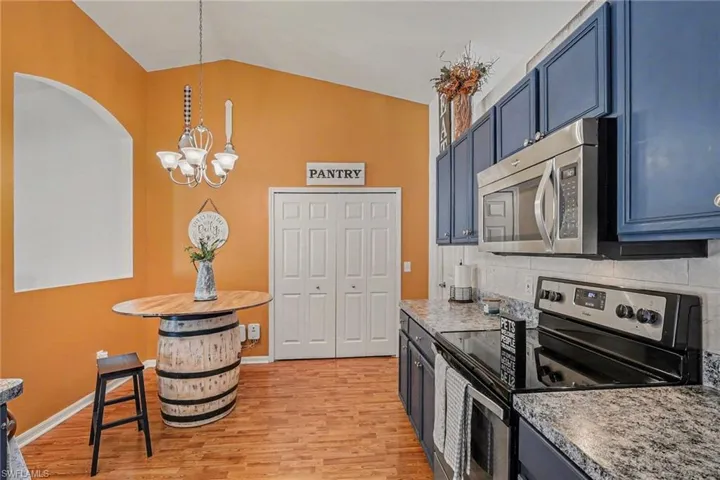 Kitchen with stainless steel appliances, lofted ceiling, light wood-type flooring, light countertops, and hanging lights