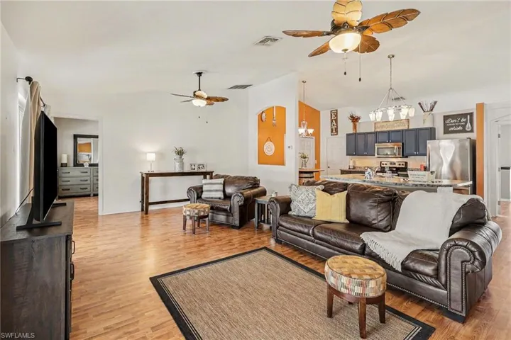 Living area featuring ceiling fan, suspended lighting, vaulted ceiling, and light wood finished floors