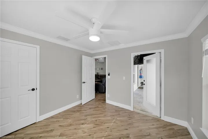 Unfurnished bedroom P with light wood finished floors, crown molding, baseboards, and a ceiling fan