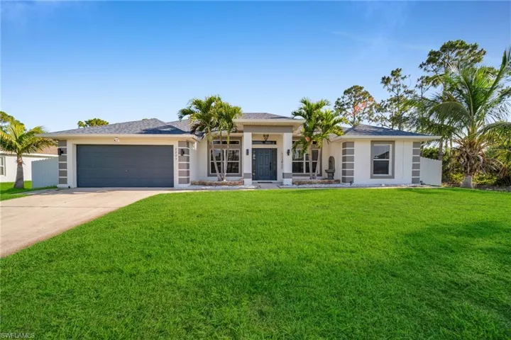 View of front facade featuring a garage, driveway, and stucco siding