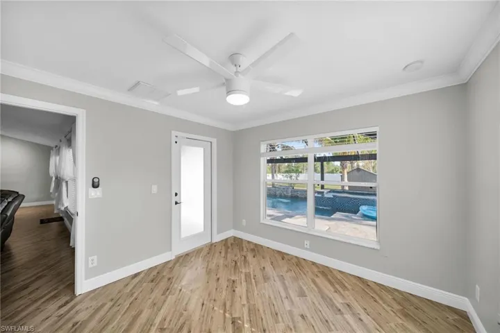 Spare room featuring baseboards, light wood finished floors, crown molding, and ceiling fan