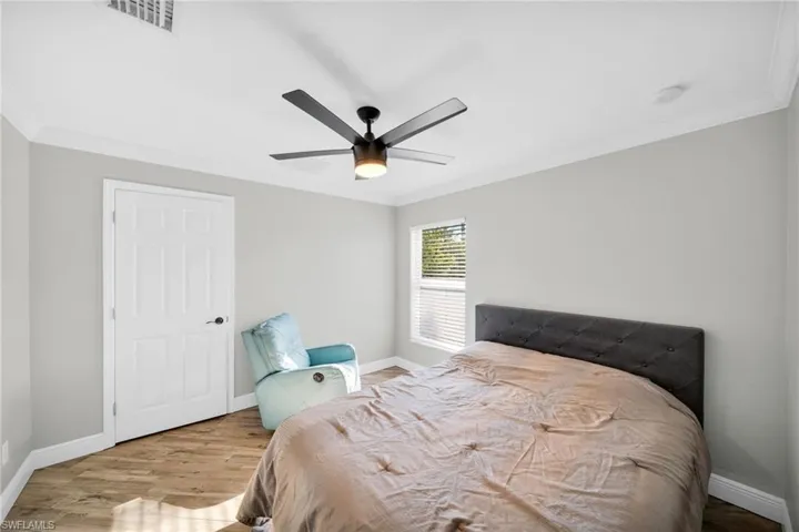 Bedroom featuring c/rown molding, baseboards, wood finished floors, and a ceiling fan