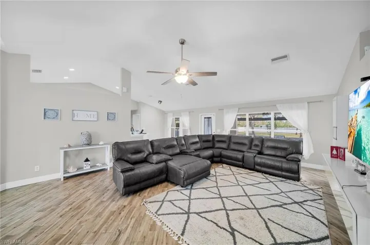 Living area featuring lofted ceiling, a ceiling fan, wood finished floors, and baseboards