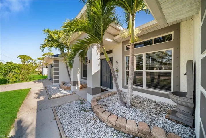Property entrance with stucco siding, an attached garage, and driveway