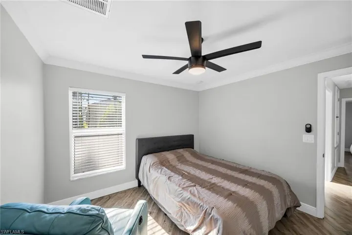 Bedroom featuring baseboards, wood \ finished floors, ornamental molding, and ceiling fan
