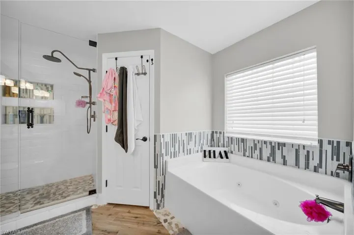 Bathroom featuring a shower stall, a whirlpool tub, and wood finished floors