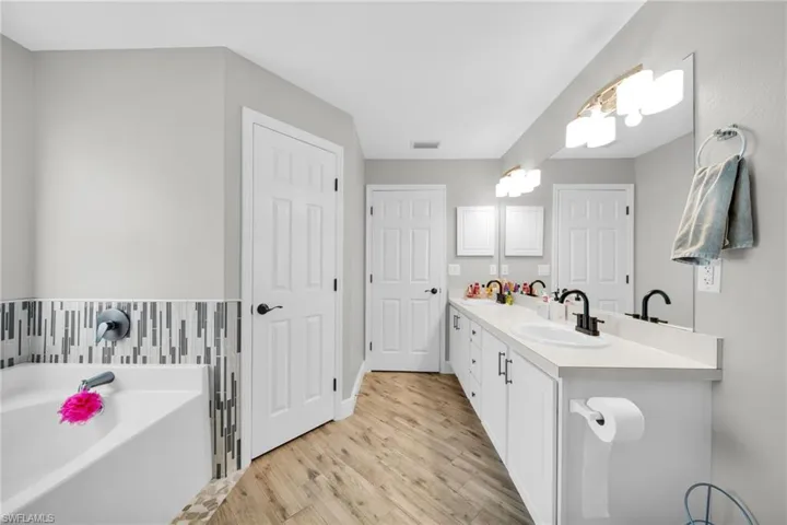 Full bathroom with wood finished floors, a garden ) tub, and double vanity