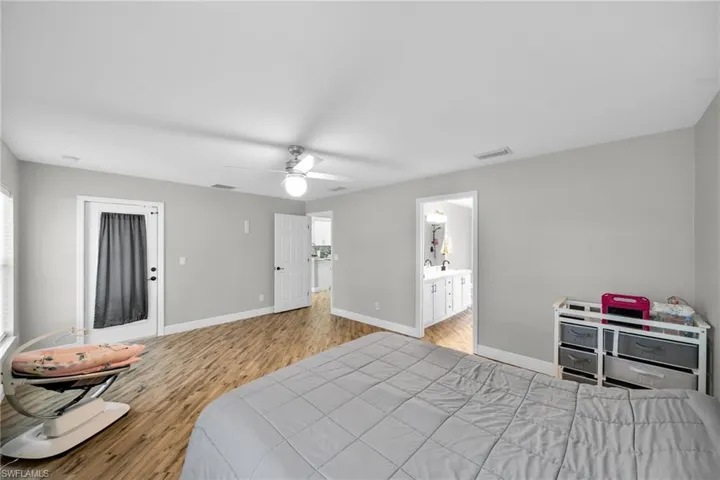 Bedroom featuring wood finished floors, baseboards, a ceiling fan, and ensuite bath