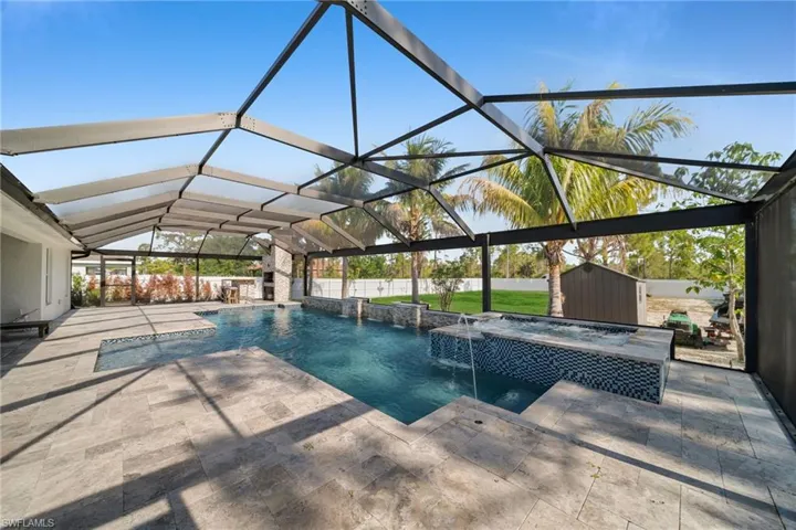 View of swimming pool featuring a patio area, a pool with connected hot tub, a fenced backyard, and a lanai