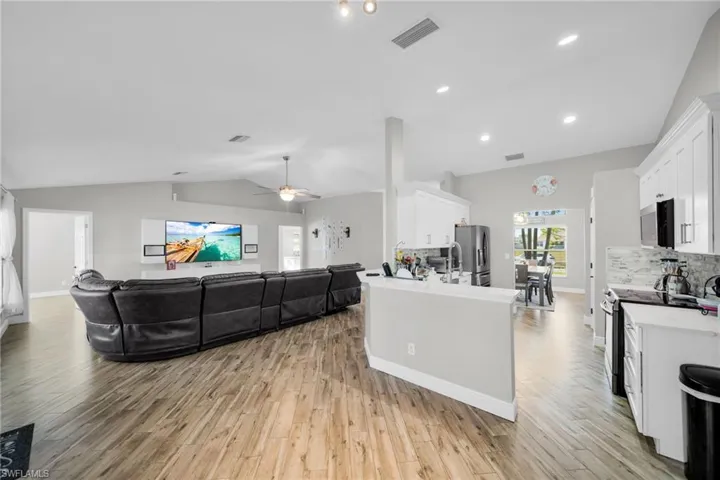 Kitchen with appliances with stainless steel finishes, lofted ceiling, white cabinetry, light wood-style flooring, and a ceiling fan