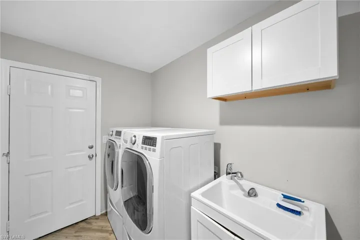 Washroom featuring cabinet space, washing machine and dryer, and light wood finished floors