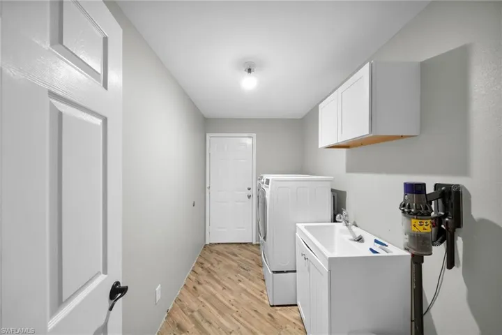 Washroom featuring cabinet space, washing ) machine and clothes dryer, and light wood-type flooring