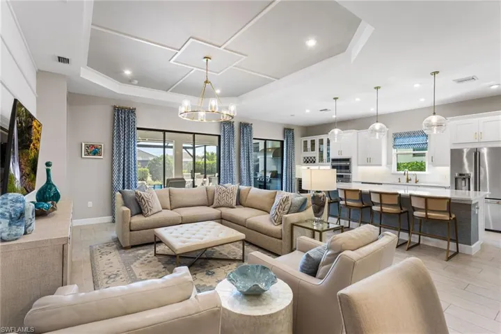Living room with hanging lights, plenty of natural light, a raised ceiling, and light wood-style floors