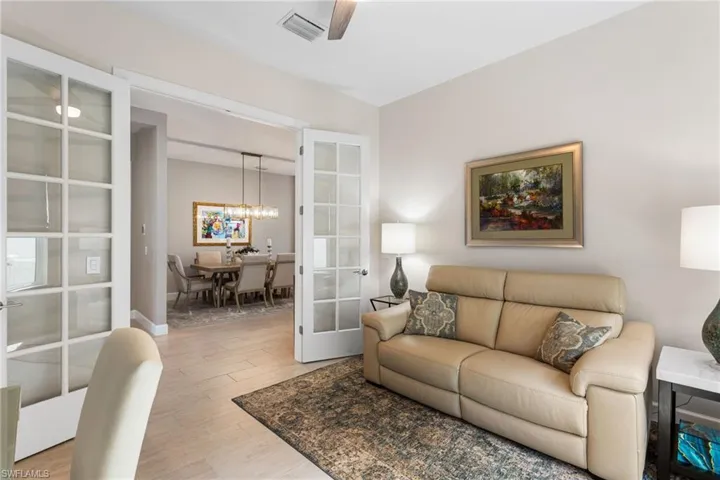 Living room with light wood finished floors, a ceiling fan, and french doors