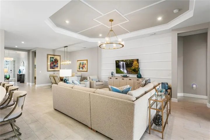 Living area featuring suspended lighting, a tray ceiling, and light wood-style floors