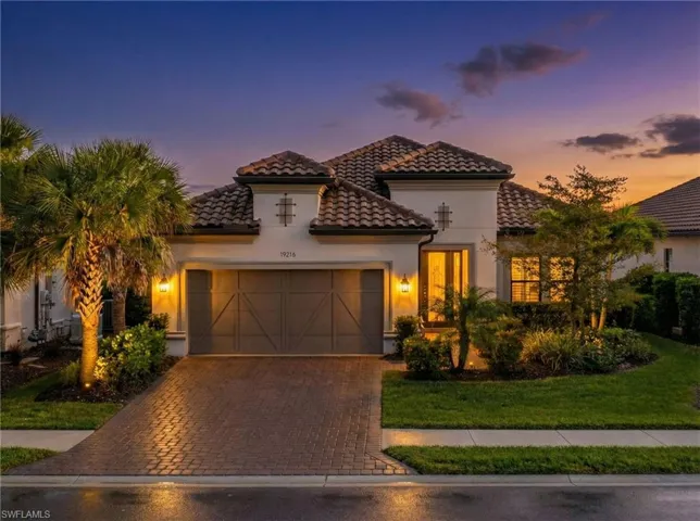 Mediterranean / spanish-style home featuring decorative driveway, an attached garage, stucco siding, a tile roof, and a front yard