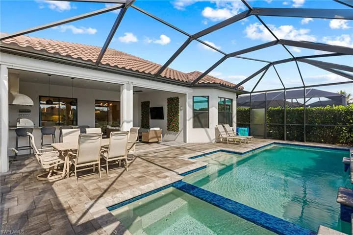 Relaxing pool / spa featuring a sunroom, a lanai, outdoor dining area, and a patio