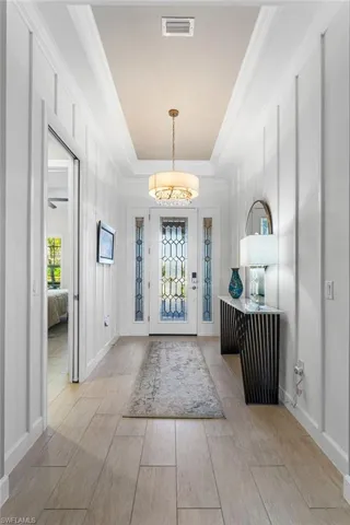 Foyer with a raised ceiling, wood finish floors, and ornamental molding