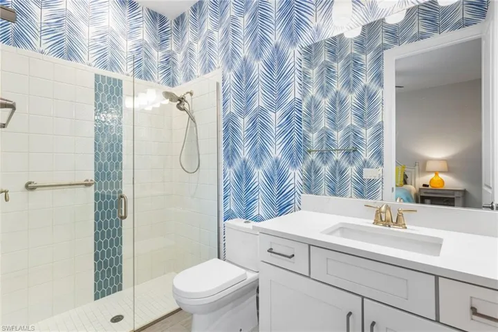 Full bath with wallpapered walls, vanity, a stall shower, and connected bathroom