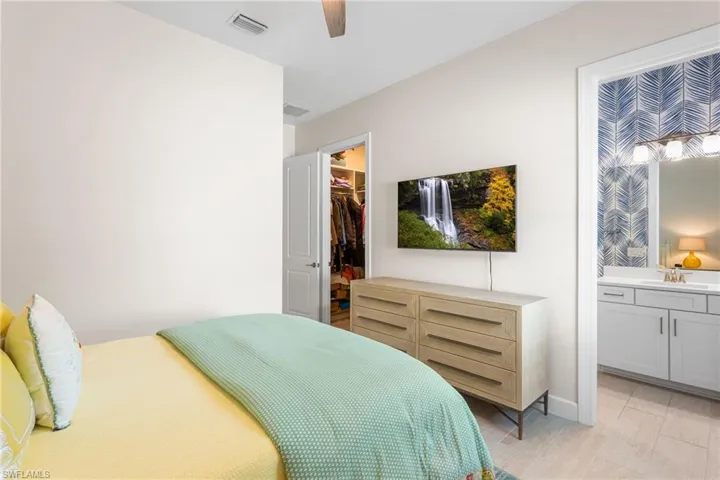 Bedroom featuring a spacious closet, a ceiling fan, and ensuite bath