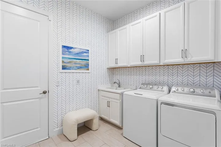 Laundry room featuring wallpapered walls, independent washer and dryer, and cabinet space