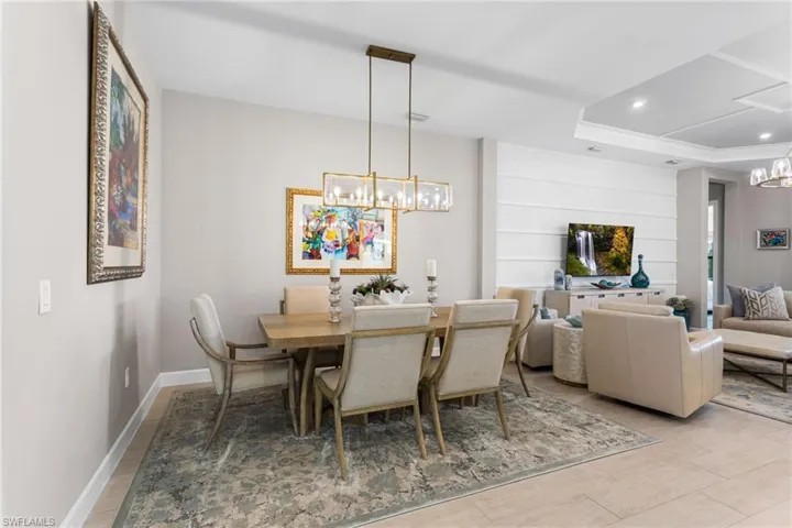 Dining area with hanging lights and a tray ceiling