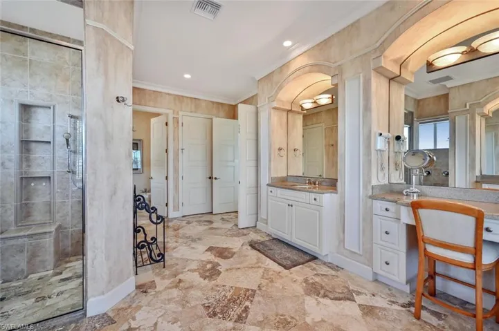 Bathroom featuring vanity, crown molding, and tiled shower