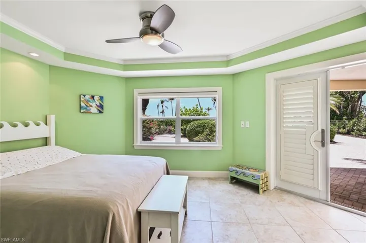 Tiled bedroom featuring ceiling fan and crown molding