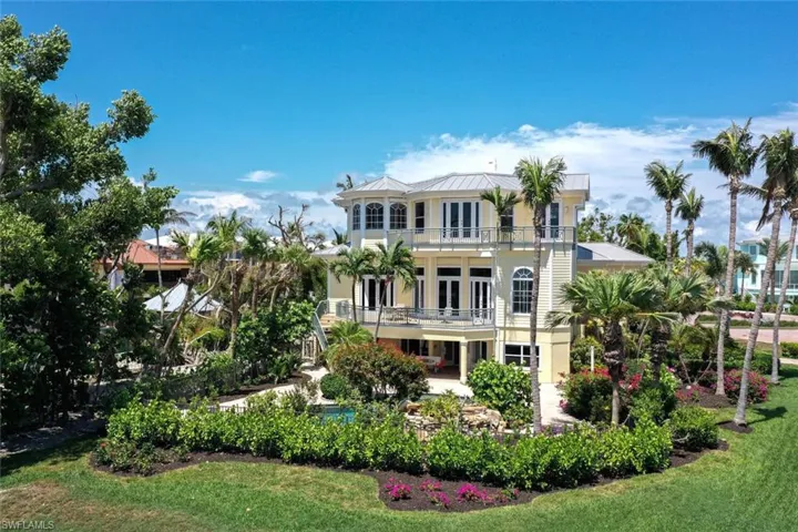 Rear view of house featuring french doors, a balcony, and a lawn