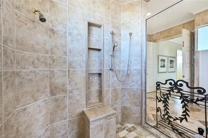 Bathroom featuring tiled shower and ornamental molding