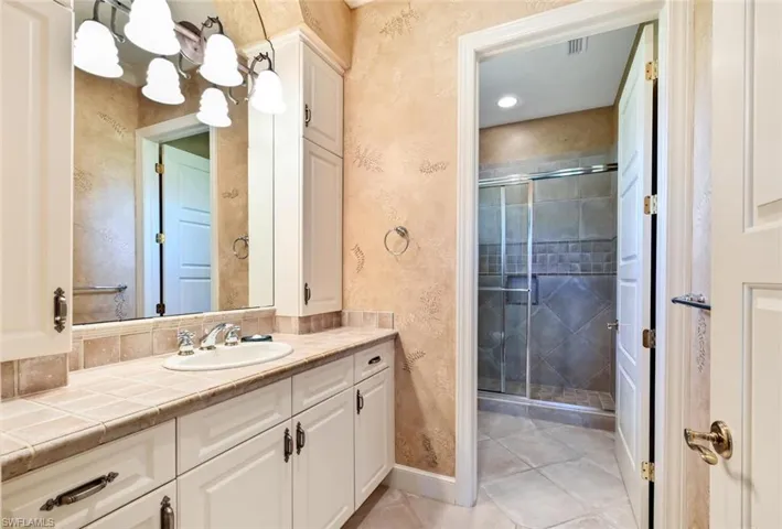 Bathroom with tile patterned floors, a shower with shower door, and vanity