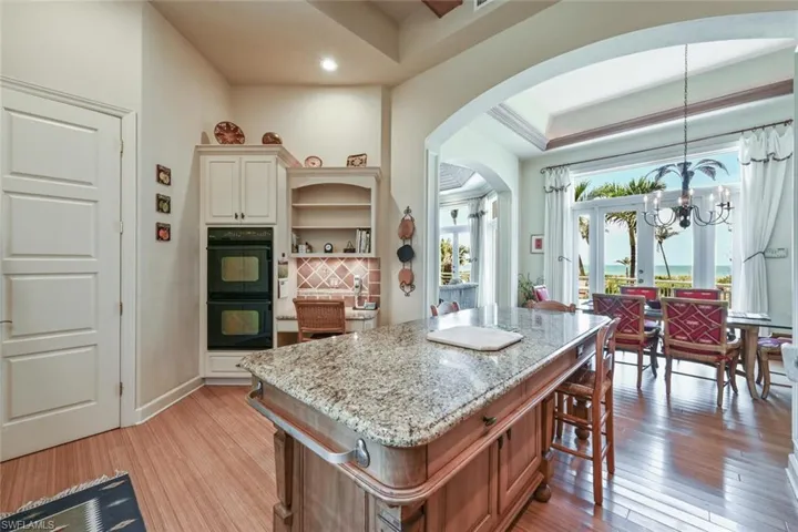 Kitchen featuring a kitchen island, light wood-type flooring, pendant lighting, and black double oven