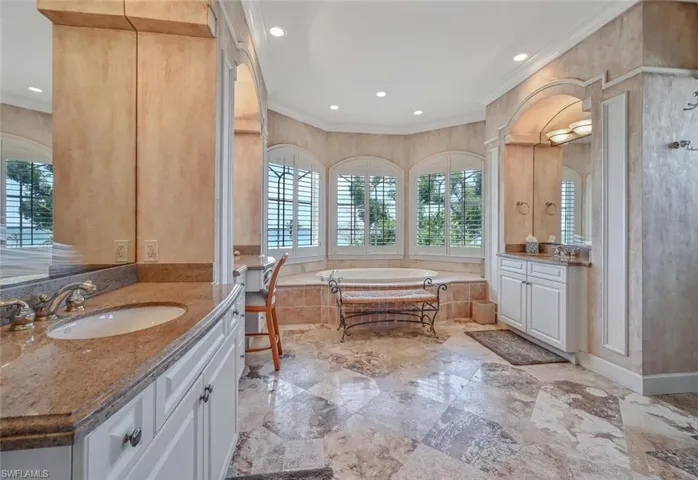 Bathroom featuring vanity, crown molding, and tiled bath