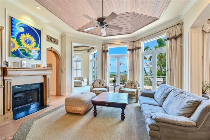Sunroom / solarium featuring french doors, a high end fireplace, wooden ceiling, ceiling fan, and a raised ceiling
